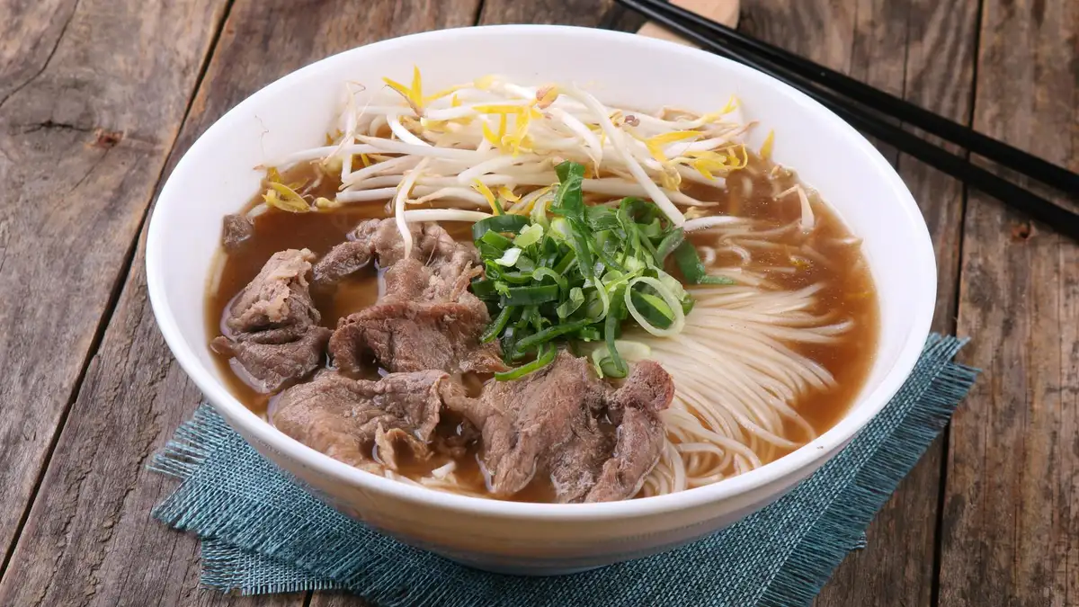 Pho vietnamita con caldo de ternera, fideos de arroz, albahaca y lima en bol caliente